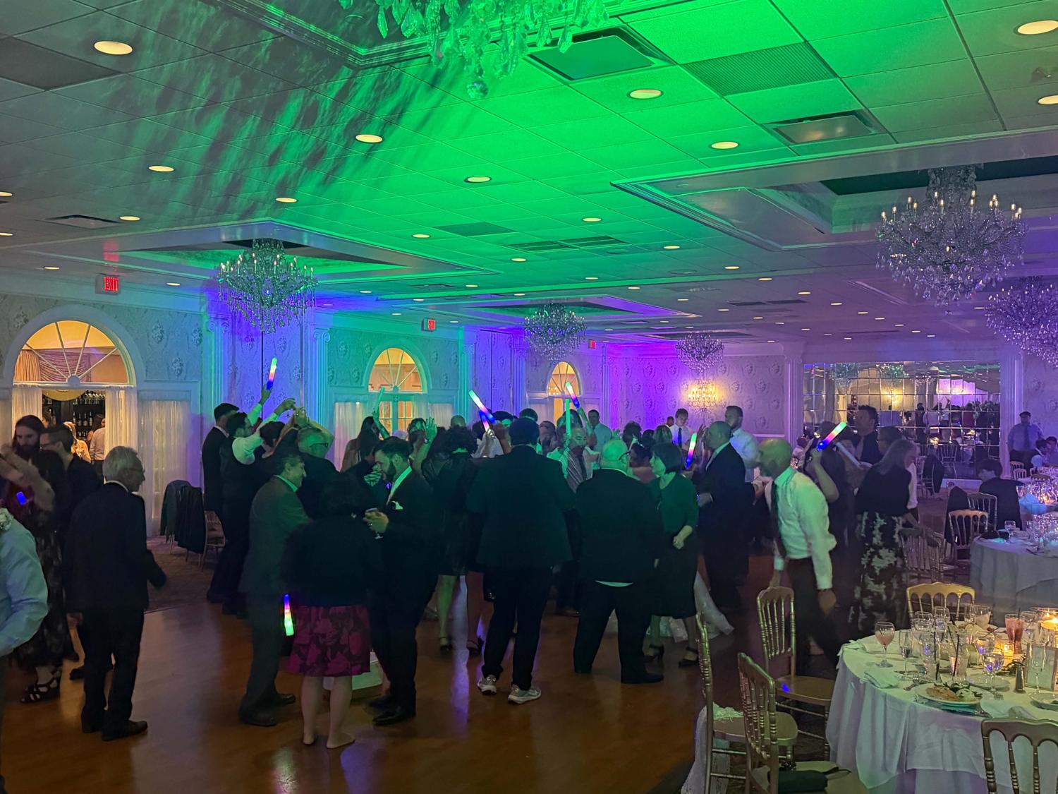 Wide view of a full ballroom dance floor with chandeliers and uplighting