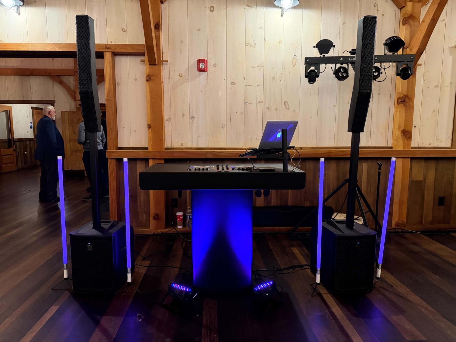 DJ booth in a barn venue with column speakers, blue uplit facade and GigBAR Move lights