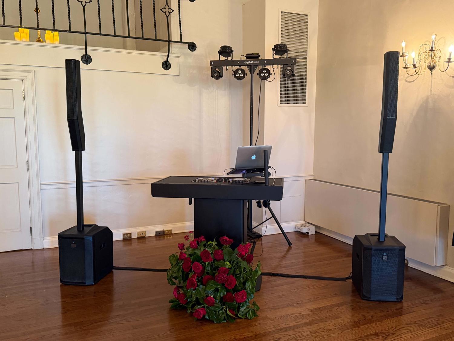 Clean DJ setup in a white ballroom with GigBAR Move and red roses in front